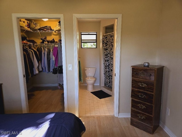 bedroom featuring connected bathroom, a spacious closet, a closet, and wood-type flooring