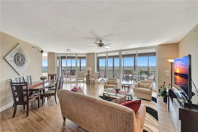 living room featuring ceiling fan, light hardwood / wood-style floors, and floor to ceiling windows