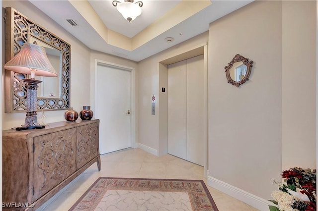 interior space featuring light tile patterned floors, elevator, and a tray ceiling