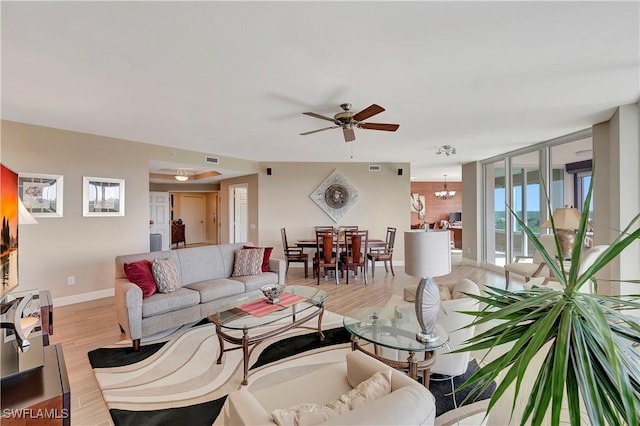 living room featuring light hardwood / wood-style floors and ceiling fan with notable chandelier