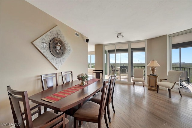 dining area featuring a wall of windows, hardwood / wood-style flooring, and plenty of natural light