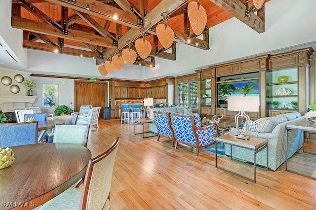 dining space featuring beamed ceiling, light wood-type flooring, and high vaulted ceiling