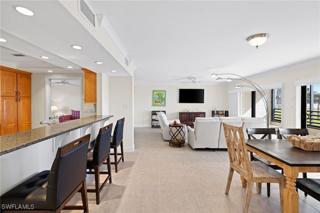 tiled dining space featuring ceiling fan and ornamental molding