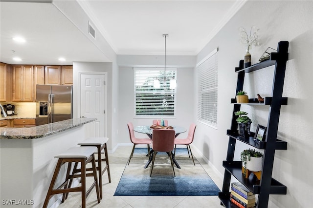 kitchen with light stone countertops, stainless steel fridge, crown molding, light tile patterned floors, and pendant lighting