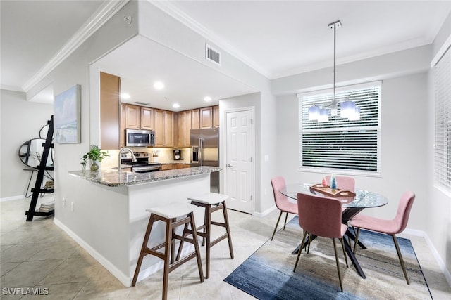 kitchen with crown molding, appliances with stainless steel finishes, decorative light fixtures, light stone counters, and kitchen peninsula