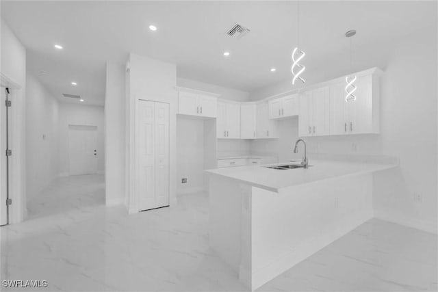 kitchen with white cabinets, pendant lighting, kitchen peninsula, and sink