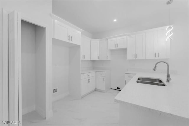 kitchen featuring pendant lighting, white cabinetry, and sink