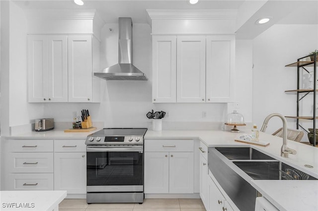 kitchen with white cabinetry, stainless steel electric range oven, and wall chimney range hood