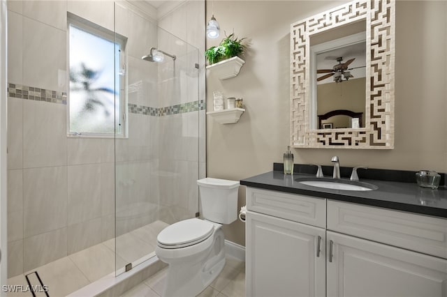 bathroom with vanity, ceiling fan, tiled shower, tile patterned flooring, and toilet