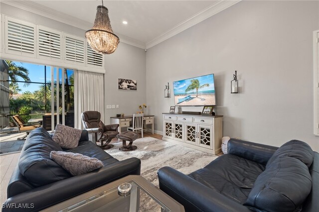 living room with a high ceiling, hardwood / wood-style flooring, ornamental molding, and a notable chandelier