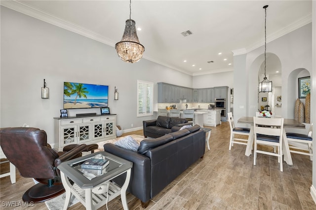 living room featuring a chandelier, light wood-type flooring, and ornamental molding