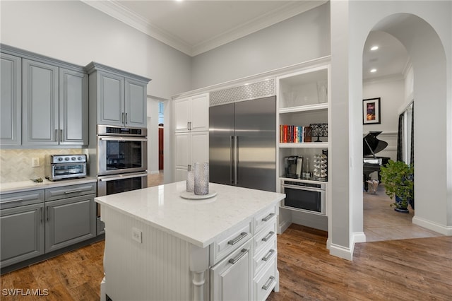 24221 Addison Place Ct, Bonita Springs, FL 34134 - kitchen with appliances with stainless steel finishes, gray cabinets, crown molding, a center island, and decorative backsplash