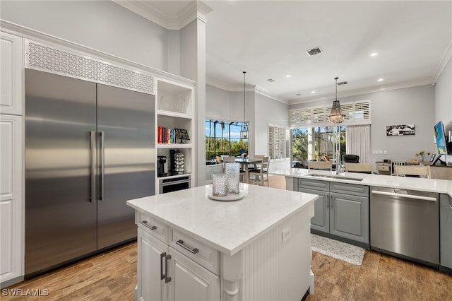 kitchen featuring appliances with stainless steel finishes, light hardwood / wood-style flooring, white cabinetry, and pendant lighting