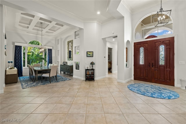 tiled entryway featuring coffered ceiling, crown molding, a towering ceiling, beamed ceiling, and a notable chandelier