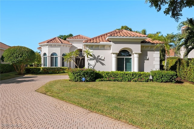 24221 Addison Place Ct, Bonita Springs, FL 34134 - mediterranean / spanish-style house featuring curved driveway, a front yard, a tile roof, and stucco siding