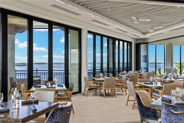 dining area featuring light tile patterned floors, a water view, and a wealth of natural light