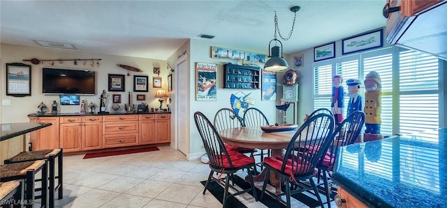 dining area featuring indoor wet bar, light tile patterned flooring, and visible vents