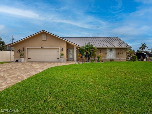 single story home featuring a garage, a front lawn, a standing seam roof, and decorative driveway