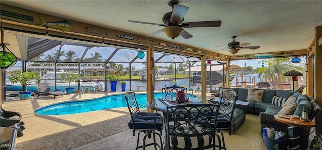 outdoor pool with glass enclosure, ceiling fan, a patio area, and an outdoor hangout area