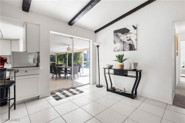 doorway to outside featuring light tile patterned floors, beam ceiling, and ceiling fan