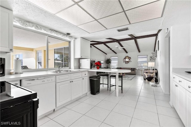 kitchen with sink, light tile patterned floors, white dishwasher, white cabinets, and vaulted ceiling