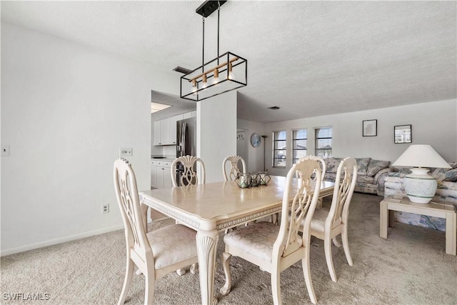 carpeted dining room featuring an inviting chandelier and a textured ceiling