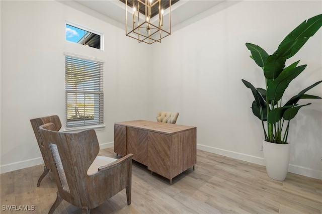 home office with light hardwood / wood-style floors and a notable chandelier