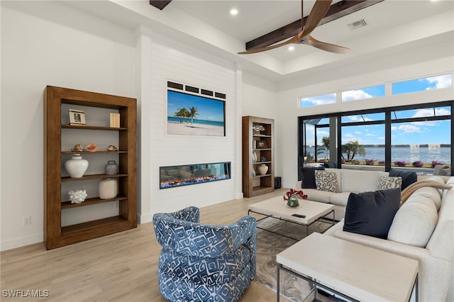 living room featuring a fireplace, hardwood / wood-style flooring, ceiling fan, and beamed ceiling