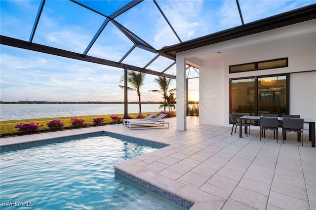 view of pool featuring a patio area, a water view, and glass enclosure