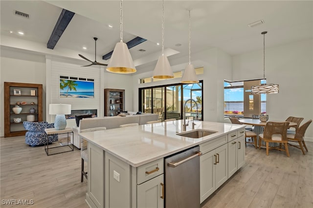 kitchen with dishwasher, sink, an island with sink, and light hardwood / wood-style flooring