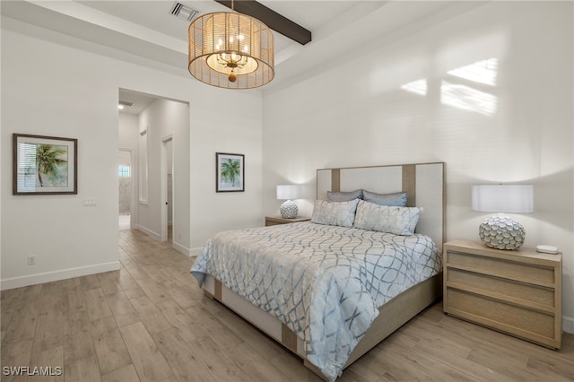 bedroom with a chandelier, beam ceiling, and light hardwood / wood-style flooring