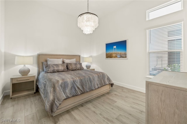 bedroom featuring light wood-type flooring and an inviting chandelier