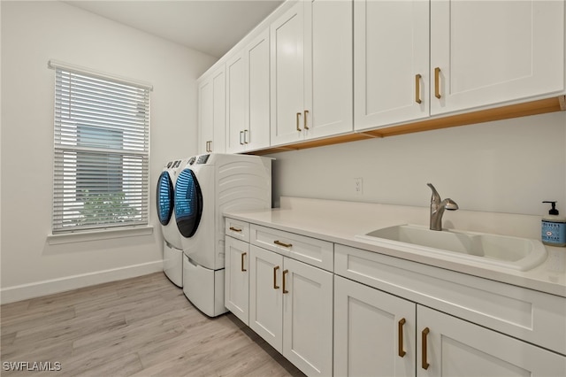 washroom with washer and dryer, light hardwood / wood-style floors, cabinets, and sink