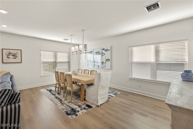 dining room featuring a notable chandelier, wood-type flooring, and a wealth of natural light