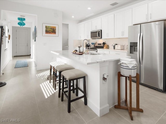 kitchen with sink, white cabinetry, a breakfast bar area, and appliances with stainless steel finishes