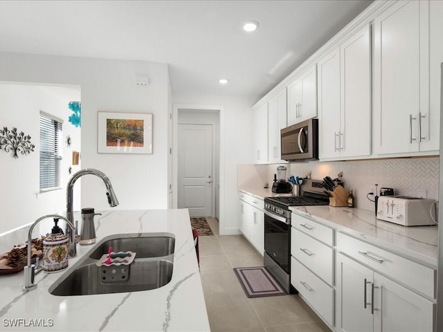 kitchen featuring light stone countertops, appliances with stainless steel finishes, tasteful backsplash, sink, and white cabinets