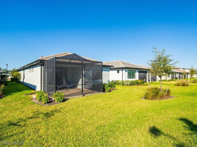 back of property with glass enclosure and a lawn