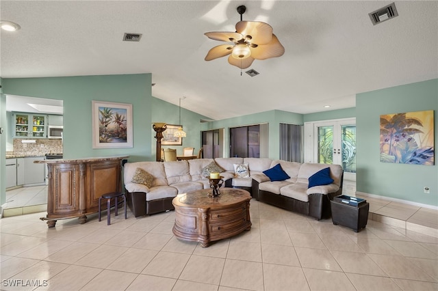 tiled living room featuring a textured ceiling, ceiling fan, french doors, and vaulted ceiling