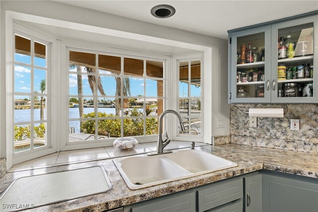 kitchen with backsplash, a water view, sink, and a wealth of natural light