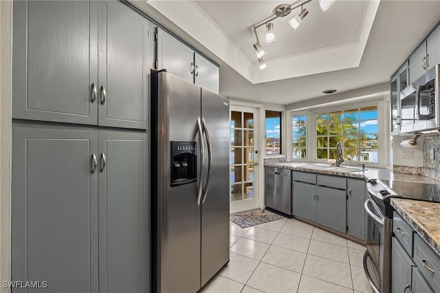 kitchen featuring sink, gray cabinets, light tile patterned floors, a tray ceiling, and stainless steel appliances