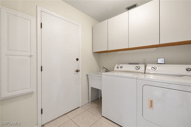 laundry room featuring cabinets, separate washer and dryer, a textured ceiling, and light tile patterned floors