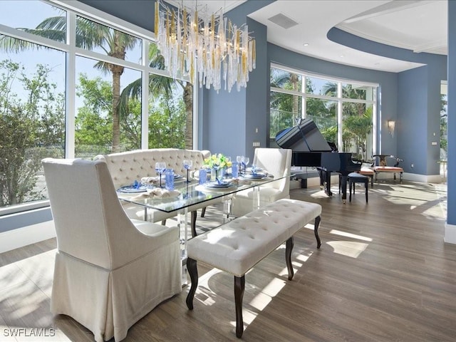 dining space with hardwood / wood-style floors, ornamental molding, and an inviting chandelier