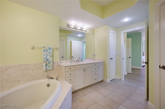 bathroom featuring tile patterned flooring, vanity, and tiled tub