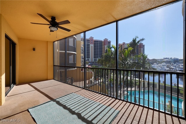 sunroom / solarium with ceiling fan and a water view