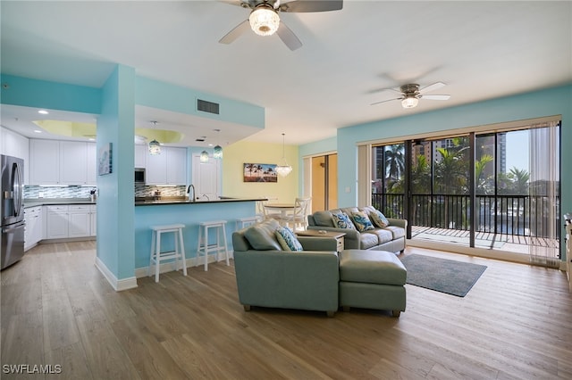 living room featuring ceiling fan, sink, and wood-type flooring