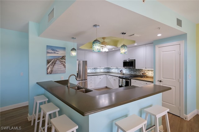 kitchen with sink, stainless steel appliances, a kitchen breakfast bar, decorative light fixtures, and white cabinets