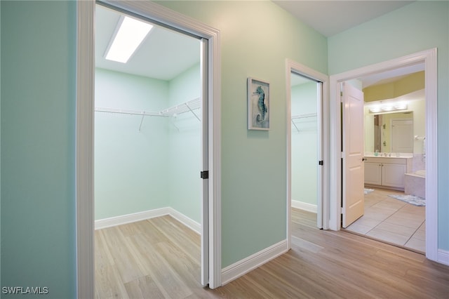 hall featuring a skylight and light hardwood / wood-style floors