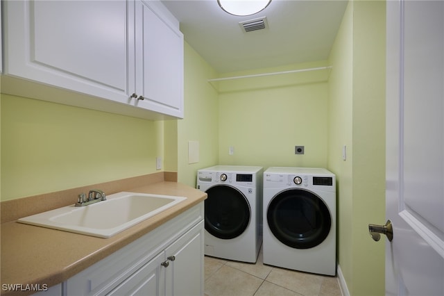 washroom with washer and clothes dryer, sink, light tile patterned floors, and cabinets