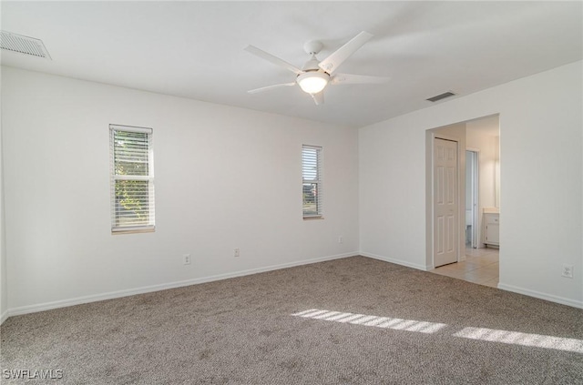 carpeted spare room with ceiling fan and plenty of natural light