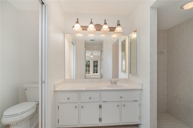 bathroom with vanity, ceiling fan, toilet, and tiled shower